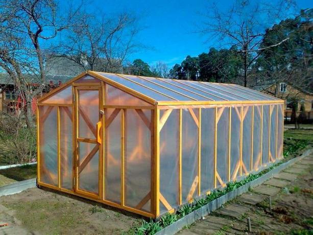 Wooden frame covered with foil greenhouse. The film is pressed strips