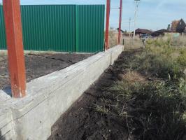 Self-filling concrete belt front of a fence